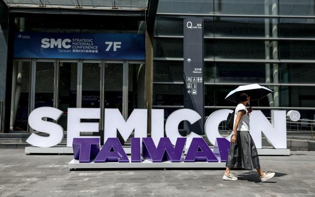 (FILES) A woman walks past signage of the Semicon Taiwan exhibition in Taipei on September 9, 2025. Taiwan said on January 16, 2026 it will remain the world's "most important" producer of AI semiconductor chips, after reaching a trade deal with the United States that will see Taiwanese companies increase investment on US soil. (Photo by I-Hwa Cheng / AFP)