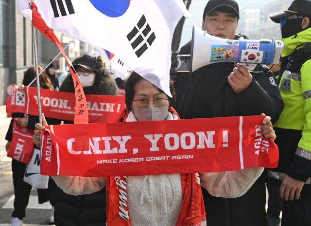 Supporters of South Korea's impeached former president Yoon Suk Yeol gather in front of the Seoul Central District Court in Seoul on January 16, 2026. A South Korean court will rule on January 16, on whether former president Yoon Suk Yeol obstructed justice during his disastrous martial law declaration and in its chaotic aftermath, the first in a series of verdicts for the disgraced ex-leader. (Photo by Jung Yeon-je / AFP)