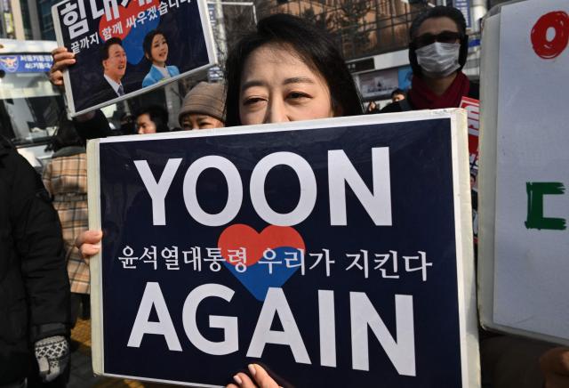 Supporters of South Korea's impeached former president Yoon Suk Yeol gather in front of the Seoul Central District Court in Seoul on January 16, 2026. A South Korean court will rule on January 16, on whether former president Yoon Suk Yeol obstructed justice during his disastrous martial law declaration and in its chaotic aftermath, the first in a series of verdicts for the disgraced ex-leader. (Photo by Jung Yeon-je / AFP)