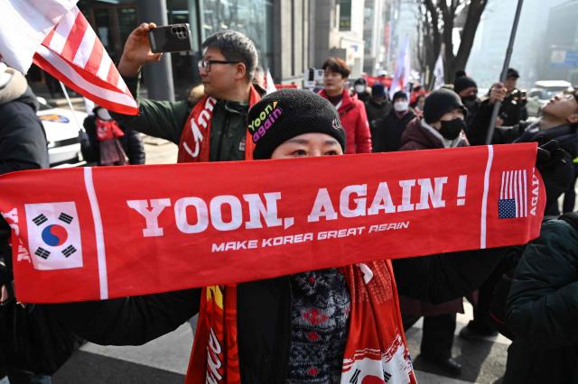Supporters of South Korea's impeached former president Yoon Suk Yeol gather in front of the Seoul Central District Court in Seoul on January 16, 2026. A South Korean court will rule on January 16, on whether former president Yoon Suk Yeol obstructed justice during his disastrous martial law declaration and in its chaotic aftermath, the first in a series of verdicts for the disgraced ex-leader. (Photo by Jung Yeon-je / AFP)