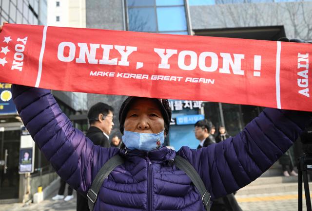 Supporters of South Korea's impeached former president Yoon Suk Yeol gather in front of the Seoul Central District Court in Seoul on January 16, 2026. A South Korean court will rule on January 16, on whether former president Yoon Suk Yeol obstructed justice during his disastrous martial law declaration and in its chaotic aftermath, the first in a series of verdicts for the disgraced ex-leader. (Photo by Jung Yeon-je / AFP)