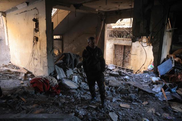 A Palestinian man stands in a room looking at the debris of a destroyed house after an Israeli military attack on the home of the al-Houli family, in which four people were reportedly killed, west of Deir al-Balah, in the central Gaza Strip on January 16, 2026. A US-backed plan to end the war in Gaza has entered its second phase despite unresolved disputes between Israel and Hamas over alleged ceasefire violations and issues unaddressed in the first stage. (Photo by BASHAR TALEB / AFP)