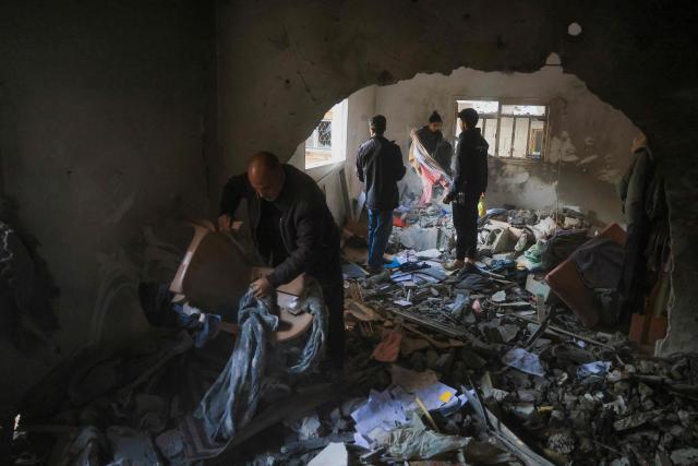 Palestinians salvage items from a house after an Israeli military attack on the home of the al-Houli family, in which four people were reportedly killed, west of Deir al-Balah, in the central Gaza Strip on January 16, 2026. A US-backed plan to end the war in Gaza has entered its second phase despite unresolved disputes between Israel and Hamas over alleged ceasefire violations and issues unaddressed in the first stage. (Photo by BASHAR TALEB / AFP)