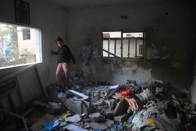 A Palestinian woman walks on the debris in a room, after an Israeli military attack on the home of the al-Houli family, in which four people were reportedly killed, west of Deir al-Balah, in the central Gaza Strip on January 16, 2026. A US-backed plan to end the war in Gaza has entered its second phase despite unresolved disputes between Israel and Hamas over alleged ceasefire violations and issues unaddressed in the first stage. (Photo by BASHAR TALEB / AFP)
