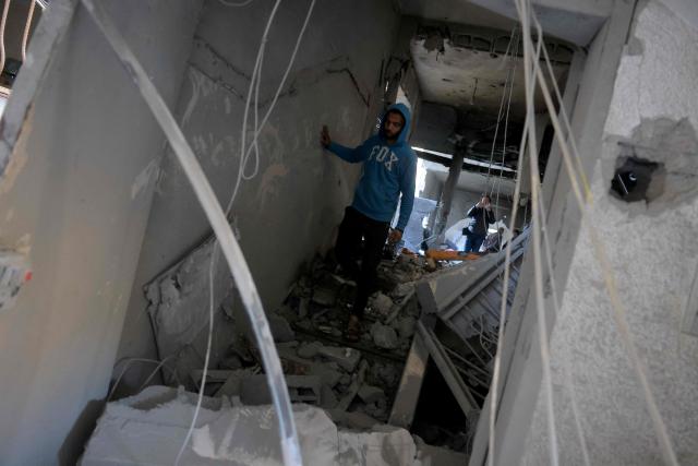 A Palestinian man walks through the debris of a destroyed house after an Israeli military attack on the home of the al-Houli family, in which four people were reportedly killed, west of Deir al-Balah, in the central Gaza Strip on January 16, 2026. A US-backed plan to end the war in Gaza has entered its second phase despite unresolved disputes between Israel and Hamas over alleged ceasefire violations and issues unaddressed in the first stage. (Photo by BASHAR TALEB / AFP)
