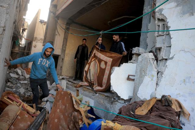 A Palestinian men watch another maneuvre past debris and broken furniture, after an Israeli military attack on the home of the al-Houli family, in which four people were reportedly killed, west of Deir al-Balah, in the central Gaza Strip on January 16, 2026. A US-backed plan to end the war in Gaza has entered its second phase despite unresolved disputes between Israel and Hamas over alleged ceasefire violations and issues unaddressed in the first stage. (Photo by BASHAR TALEB / AFP)