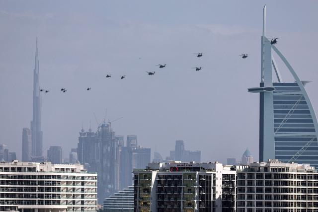 United Arab Emirates army helicopters fly from Burj al Arab hotel (R) towards Burj Khalifa, in Dubai on January 16, 2026. (Photo by Fadel SENNA / AFP)