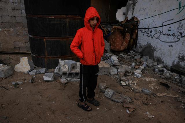 A Palestinian boy stands outside a destroyed house after an Israeli military attack on the home of the al-Houli family, in which four people were reportedly killed, west of Deir al-Balah, in the central Gaza Strip on January 16, 2026. A US-backed plan to end the war in Gaza has entered its second phase despite unresolved disputes between Israel and Hamas over alleged ceasefire violations and issues unaddressed in the first stage. (Photo by BASHAR TALEB / AFP)