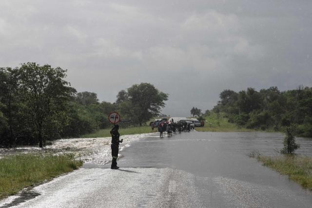 A general view of floodwater flowing over a road, blocking motorists from crossing, in Giyani on January 16, 2026. Flooding triggered by torrential rains in northeastern South Africa claimed at least 10 lives overnight and forced the closure of the iconic Kruger National Park, officials said on January 15, 2026. 
The weather service issued the maximum warning for more rain in parts of the country while neighbouring Mozambique was also on alert after flooding that inundated roads and homes. (Photo by Orlando Chauke / AFP)