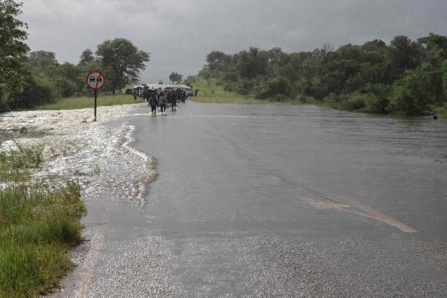 A general view of floodwater flowing over a road, blocking motorists from crossing, in Giyani on January 16, 2026. Flooding triggered by torrential rains in northeastern South Africa claimed at least 10 lives overnight and forced the closure of the iconic Kruger National Park, officials said on January 15, 2026. 
The weather service issued the maximum warning for more rain in parts of the country while neighbouring Mozambique was also on alert after flooding that inundated roads and homes. (Photo by Orlando Chauke / AFP)