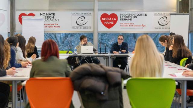 YDN Europe Regional Meeting. Participants attending a roundtable discussion and presentation on human rights and anti-hate initiatives in a conference room, with banners displayed in the background. (Photo by Pierre Rein / MediaConnect) / Disclaimer: This document is neither produced nor endorsed by AFP. It is distributed under its issuer sole responsibility. Its reproduction is authorized in context without any distortion of content. If you have any question about this document, please contact its issuer.