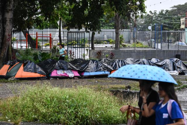 A woman walks amid tents set up by relatives outside El Rodeo I prison while they wait for news on the release of prisoners in Guatire, Miranda State, some 30 kilometers east of Caracas, on January 16, 2026. Venezuela has released a Czech detained in September 2024 with four Americans and two Spaniards over an alleged plot to assassinate then-president Nicolas Maduro, the Czech foreign minister said on January 16. (Photo by Ronaldo SCHEMIDT / AFP)