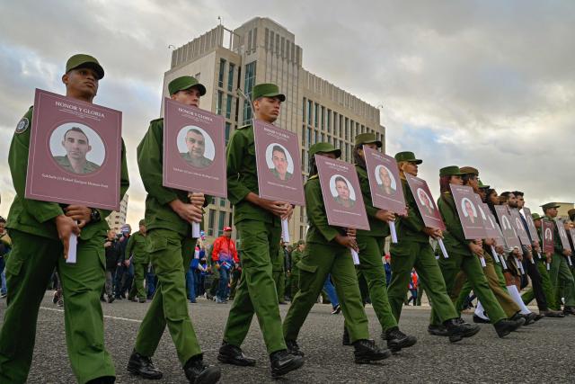 TOPSHOT - Cuban soldiers hold portraits of the 32 Cuban soldiers who lost their lives during the US incursion in Venezuela as they take part in the "Anti-Imperialist" protest in front of the US Embassy in Havana on January 16, 2026. The capture by US forces of Venezuelan leader Nicolas Maduro on January 3, 2026, and the killing in the operation of 32 Cubans assigned to protect him represent a major blow for the island's revered intelligence services, experts say. (Photo by ADALBERTO ROQUE / AFP)