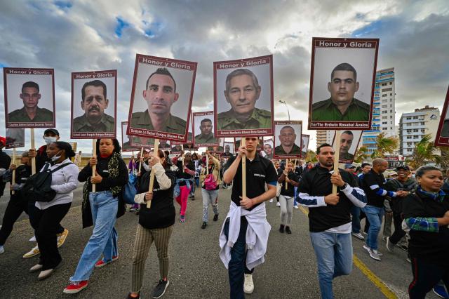 Cuban hold portraits of the 32 Cuban soldiers who lost their lives during the US incursion in Venezuela as they take part in the "Anti-Imperialist" protest in front of the US Embassy in Havana on January 16, 2026. The capture by US forces of Venezuelan leader Nicolas Maduro on January 3, 2026, and the killing in the operation of 32 Cubans assigned to protect him represent a major blow for the island's revered intelligence services, experts say. (Photo by ADALBERTO ROQUE / AFP)