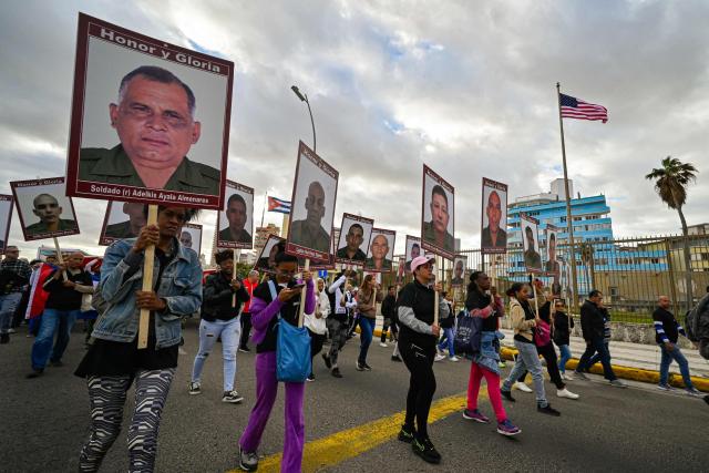 Cuban hold portraits of the 32 Cuban soldiers who lost their lives during the US incursion in Venezuela as they take part in the "Anti-Imperialist" protest in front of the US Embassy in Havana on January 16, 2026. The capture by US forces of Venezuelan leader Nicolas Maduro on January 3, 2026, and the killing in the operation of 32 Cubans assigned to protect him represent a major blow for the island's revered intelligence services, experts say. (Photo by ADALBERTO ROQUE / AFP)