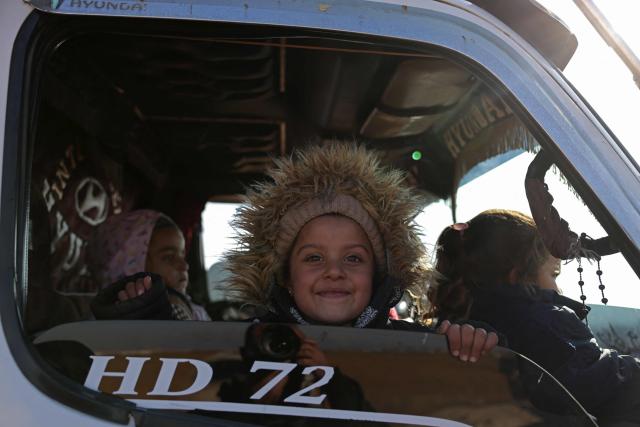 Children sit in a vehicle along with their families as they wait to flee from a Kurdish-controlled area, in Rasm al-Harmal, east of Aleppo city on January 16, 2026. Civilians fled a Kurdish-held region of northern Syria on January 16 before a deadline set by the army, which seeks to expand its control over the area after driving Kurdish forces from Aleppo. The government is seeking to extend its authority nationwide following the ousting of longtime leader Bashar al-Assad in December 2024. (Photo by Bakr ALkasem / AFP)