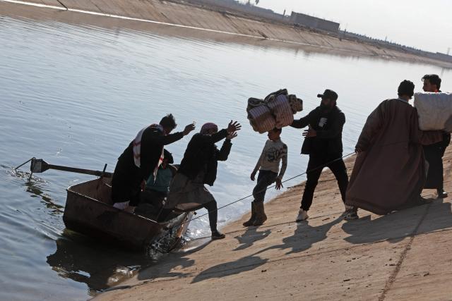 People along with their belongings use a boat to flee from a Kurdish-controlled area, in Rasm al-Harmal, east of Aleppo city on January 16, 2026. Civilians fled a Kurdish-held region of northern Syria on January 16 before a deadline set by the army, which seeks to expand its control over the area after driving Kurdish forces from Aleppo. The government is seeking to extend its authority nationwide following the ousting of longtime leader Bashar al-Assad in December 2024. (Photo by Bakr ALkasem / AFP)