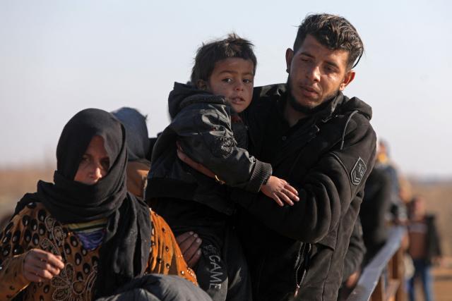 A family flees from a Kurdish-controlled area, in Rasm al-Harmal, east of Aleppo city on January 16, 2026. Civilians fled a Kurdish-held region of northern Syria on January 16 before a deadline set by the army, which seeks to expand its control over the area after driving Kurdish forces from Aleppo. The government is seeking to extend its authority nationwide following the ousting of longtime leader Bashar al-Assad in December 2024. (Photo by Bakr ALkasem / AFP)