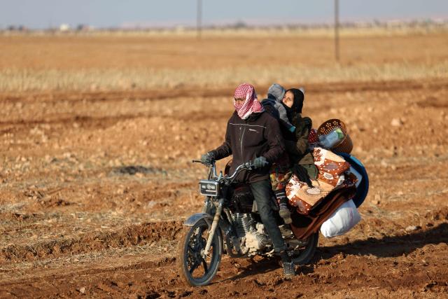 TOPSHOT - A family ride a motorbike along with their belongings as they flee from the vicinity of the Humaymah village, east of Aleppo city on January 16, 2026. Civilians fled a Kurdish-held region of northern Syria on January 16 before a deadline set by the army, which seeks to expand its control over the area after driving Kurdish forces from Aleppo. The government is seeking to extend its authority nationwide following the ousting of longtime leader Bashar al-Assad in December 2024. (Photo by OMAR HAJ KADOUR / AFP)