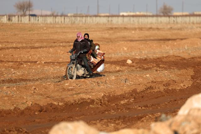 A family ride a motorbike along with their belongings as they flee from the vicinity of the Humaymah village, east of Aleppo city on January 16, 2026. Civilians fled a Kurdish-held region of northern Syria on January 16 before a deadline set by the army, which seeks to expand its control over the area after driving Kurdish forces from Aleppo. The government is seeking to extend its authority nationwide following the ousting of longtime leader Bashar al-Assad in December 2024. (Photo by OMAR HAJ KADOUR / AFP)