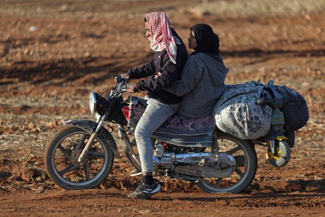 Civilians ride a motorbike along with their belongings as they flee from the vicinity of the Humaymah village, east of Aleppo city on January 16, 2026. Civilians fled a Kurdish-held region of northern Syria on January 16 before a deadline set by the army, which seeks to expand its control over the area after driving Kurdish forces from Aleppo. The government is seeking to extend its authority nationwide following the ousting of longtime leader Bashar al-Assad in December 2024. (Photo by OMAR HAJ KADOUR / AFP)