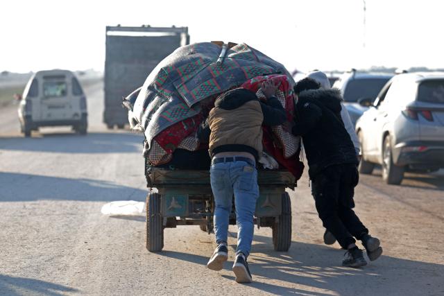 Men push a vehicle loaded with their belongings as they flee from the vicinity of the Humaymah village, east of Aleppo city on January 16, 2026. Civilians fled a Kurdish-held region of northern Syria on January 16 before a deadline set by the army, which seeks to expand its control over the area after driving Kurdish forces from Aleppo. The government is seeking to extend its authority nationwide following the ousting of longtime leader Bashar al-Assad in December 2024. (Photo by OMAR HAJ KADOUR / AFP)