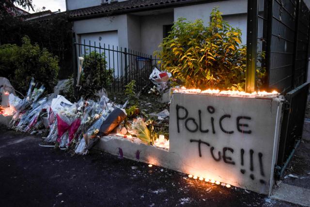 (FILES) Candles and flowers are placed near the words "police kill" spray painted on the wall reportedly damaged by the car of Aboubacar Fofana who was shot dead by an officer during a police check on the night of July 3, in the Le Breil neighborhood of Nantes, western France, on July 6, 2018. The police officer tried for shooting young Aboubacar Fofana during a check in Nantes in 2018 was sentenced on January 16, 2026, to seven years in prison with immediate effect by the Loire-Atlantique Criminal Court. (Photo by SEBASTIEN SALOM GOMIS / AFP)