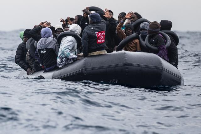 Migrants onboard a rubber boat wave and gesture as they wait to be rescued by crew members of the “Ocean Viking” rescue ship in the search-and-rescue zone off the international waters of Libya, on January 16, 2026. 46 migrants on a rubber dinghy in distress were rescued by the crew of the "Ocean Viking" in international waters off the coast of Libya as they attempted to reach the shores of the Italian island of Lampedusa. Libya, located about 300 km from the Italian coast, is one of the main departure points in North Africa for migrants, mostly from sub-Saharan Africa, risking their lives attempting to cross the Mediterranean sea. This is the first rescue of the year carried out by the ship operated by the NGO SOS Mediterranee. (Photo by Sameer Al-DOUMY / AFP)