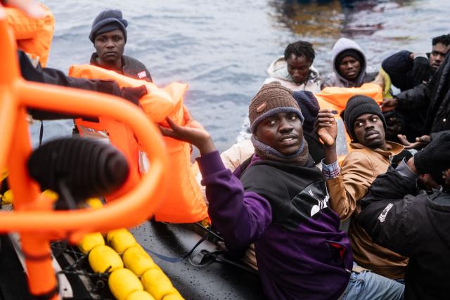 Migrants onboard a rubber boat receive life jackets as crew members of the “Ocean Viking” rescue ship carry out a rescue operation using a RHIB (Rigid inflatable boat) in the search-and-rescue zone off the international waters of Libya, on January 16, 2026. 46 migrants on a rubber dinghy in distress were rescued by the crew of the "Ocean Viking" in international waters off the coast of Libya as they attempted to reach the shores of the Italian island of Lampedusa. Libya, located about 300 km from the Italian coast, is one of the main departure points in North Africa for migrants, mostly from sub-Saharan Africa, risking their lives attempting to cross the Mediterranean sea. This is the first rescue of the year carried out by the ship operated by the NGO SOS Mediterranee. (Photo by Sameer Al-DOUMY / AFP)