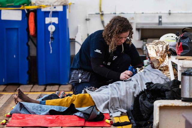 A crew member of the “Ocean Viking” rescue ship provides medical care to an exhausted migrant after they were rescued in the search-and-rescue zone off the international waters of Libya, on January 16, 2026. 46 migrants on a rubber dinghy in distress were rescued by the crew of the "Ocean Viking" in international waters off the coast of Libya as they attempted to reach the shores of the Italian island of Lampedusa. Libya, located about 300 km from the Italian coast, is one of the main departure points in North Africa for migrants, mostly from sub-Saharan Africa, risking their lives attempting to cross the Mediterranean sea. This is the first rescue of the year carried out by the ship operated by the NGO SOS Mediterranee. (Photo by Sameer Al-DOUMY / AFP)