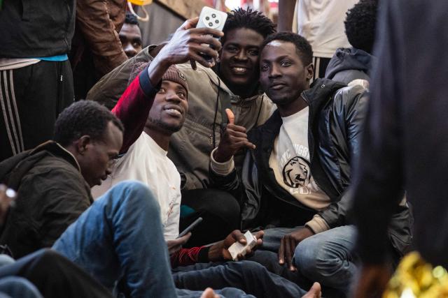 Migrants take a selfie onboard of the “Ocean Viking” rescue ship after being rescued in the search-and-rescue zone off the international waters of Libya, on January 16, 2026. 46 migrants on a rubber dinghy in distress were rescued by the crew of the "Ocean Viking" in international waters off the coast of Libya as they attempted to reach the shores of the Italian island of Lampedusa. Libya, located about 300 km from the Italian coast, is one of the main departure points in North Africa for migrants, mostly from sub-Saharan Africa, risking their lives attempting to cross the Mediterranean sea. This is the first rescue of the year carried out by the ship operated by the NGO SOS Mediterranee. (Photo by Sameer Al-DOUMY / AFP)
