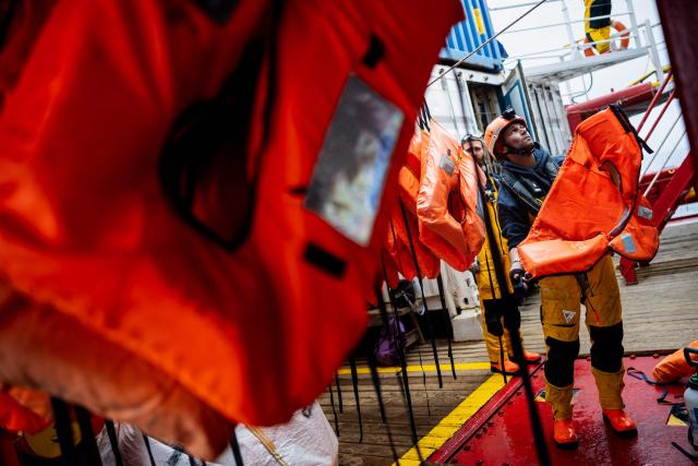 A crew member of the “Ocean Viking” rescue ship hangs life jackets to dry after rescueing 46 migrants in the search-and-rescue zone off the international waters of Libya, on January 16, 2026. The 46 migrants of a rubber dinghy in distress were rescued by the crew of the "Ocean Viking" in international waters off the coast of Libya as they attempted to reach the shores of the Italian island of Lampedusa. Libya, located about 300 km from the Italian coast, is one of the main departure points in North Africa for migrants, mostly from sub-Saharan Africa, risking their lives attempting to cross the Mediterranean sea. This is the first rescue of the year carried out by the ship operated by the NGO SOS Mediterranee. (Photo by Sameer Al-DOUMY / AFP)