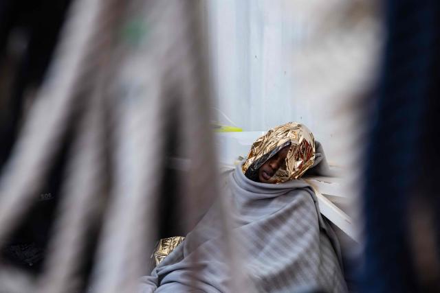TOPSHOT - An exhausted migrant wrapped in a survival blanket rests onboard the “Ocean Viking” rescue ship after being rescued in the search-and-rescue zone off the international waters of Libya, on January 16, 2026. 46 migrants on a rubber dinghy in distress were rescued by the crew of the "Ocean Viking" in international waters off the coast of Libya as they attempted to reach the shores of the Italian island of Lampedusa. Libya, located about 300 km from the Italian coast, is one of the main departure points in North Africa for migrants, mostly from sub-Saharan Africa, risking their lives attempting to cross the Mediterranean sea. This is the first rescue of the year carried out by the ship operated by the NGO SOS Mediterranee. (Photo by Sameer Al-DOUMY / AFP)