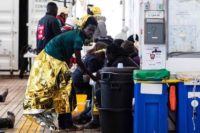 A migrant wrapped in a survival blanket stands onboard of the “Ocean Viking” rescue ship after being rescued in the search-and-rescue zone off the international waters of Libya, on January 16, 2026. 46 migrants on a rubber dinghy in distress were rescued by the crew of the "Ocean Viking" in international waters off the coast of Libya as they attempted to reach the shores of the Italian island of Lampedusa. Libya, located about 300 km from the Italian coast, is one of the main departure points in North Africa for migrants, mostly from sub-Saharan Africa, risking their lives attempting to cross the Mediterranean sea. This is the first rescue of the year carried out by the ship operated by the NGO SOS Mediterranee. (Photo by Sameer Al-DOUMY / AFP)