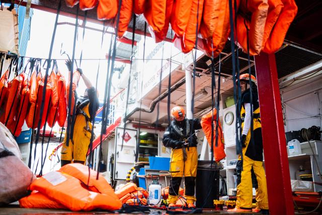 A crew member of the “Ocean Viking” rescue ship disinfects life jackets after rescueing 46 migrants in the search-and-rescue zone off the international waters of Libya, on January 16, 2026. The 46 migrants of a rubber dinghy in distress were rescued by the crew of the "Ocean Viking" in international waters off the coast of Libya as they attempted to reach the shores of the Italian island of Lampedusa. Libya, located about 300 km from the Italian coast, is one of the main departure points in North Africa for migrants, mostly from sub-Saharan Africa, risking their lives attempting to cross the Mediterranean sea. This is the first rescue of the year carried out by the ship operated by the NGO SOS Mediterranee. (Photo by Sameer Al-DOUMY / AFP)