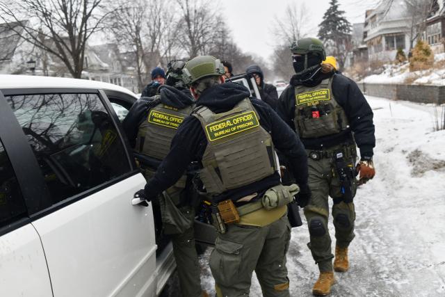Federal agents return to their car after a patrol in the Frogtown neighborhood while anti-ICE activists warn the community about their presence and oppose ongoing Immigration and Customs Enforcement detentions, part of heightened tensions following a federal immigration enforcement surge and recent shooting involving an ICE officer in St. Paul, Minnesota, on January 16, 2026. US President Donald Trump said Friday there was no immediate need to invoke the Insurrection Act over protests against immigration raids in Minnesota, a day after threatening to use the law. Trump had threatened the drastic measure that would have allowed him to deploy the military to the northern state for law enforcement purposes in response to protests against broad-reaching immigration raids spearheaded by his administration. (Photo by Octavio JONES / AFP)