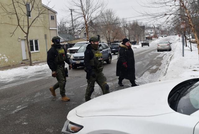 Federal agents patrol in the Frogtown neighborhood while anti-ICE activists warn the community about their presence and oppose ongoing Immigration and Customs Enforcement detentions, part of heightened tensions following a federal immigration enforcement surge and recent shooting involving an ICE officer in St. Paul, Minnesota, on January 16, 2026. US President Donald Trump said Friday there was no immediate need to invoke the Insurrection Act over protests against immigration raids in Minnesota, a day after threatening to use the law. Trump had threatened the drastic measure that would have allowed him to deploy the military to the northern state for law enforcement purposes in response to protests against broad-reaching immigration raids spearheaded by his administration. (Photo by Octavio JONES / AFP)