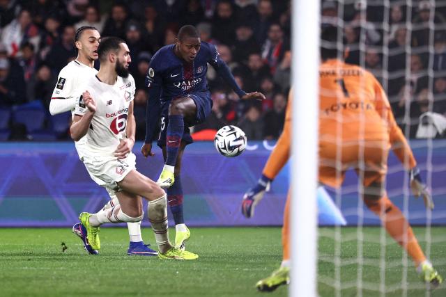 Paris Saint-Germain's Portuguese defender #25 Nuno Mendes (C) shoots towards goal during the French L1 football match between Paris Saint-Germain (PSG) and Lille LOSC at the Parc des Princes stadium in Paris on January 16, 2026. (Photo by Anne-Christine POUJOULAT / AFP)