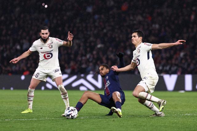 Paris Saint-Germain's French forward #29 Bradley Barcola (C) and Lille's Algerian defender #23 Aissa Mandi (R) fight for the ball during the French L1 football match between Paris Saint-Germain (PSG) and Lille LOSC at the Parc des Princes stadium in Paris on January 16, 2026. (Photo by Anne-Christine POUJOULAT / AFP)