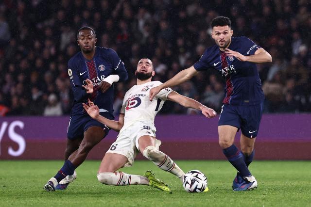 Lille's Algerian midfielder #06 Nabil Bentaleb (C) falls to the ground as he fights for the ball with Paris Saint-Germain's Ecuadoran defender #51 Willian Pacho (L) and Paris Saint-Germain's Portuguese forward #09 Goncalo Ramos (R) during the French L1 football match between Paris Saint-Germain (PSG) and Lille LOSC at the Parc des Princes stadium in Paris on January 16, 2026. (Photo by Anne-Christine POUJOULAT / AFP)