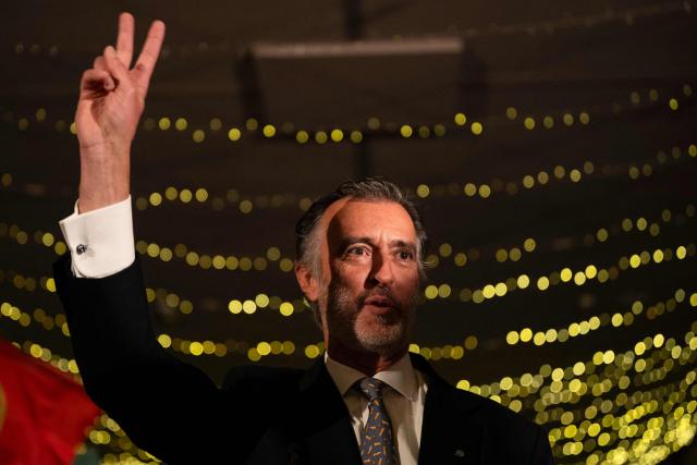 Liberal Initiative Party candidate for Portugal’s presidency, Joao Cotrim Figueiredo,  flashes the victory sign during a campaign dinner in Braga, northern Portugal, on January 16, 2026. Portugal will hold presidential elections on 18 January. (Photo by MIGUEL RIOPA / AFP)