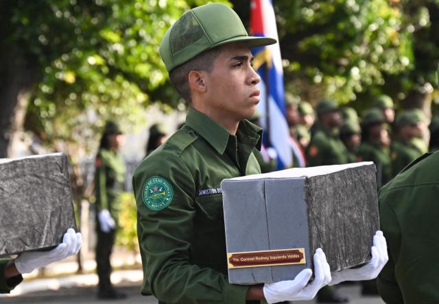 A Cuban soldier carries the remains of one of the 32 Cuban soldiers killed during the US incursion in Venezuela during their funeral at Colon cemetery in Havana on January 16, 2026. The capture by US forces of Venezuelan leader Nicolas Maduro on January 3, 2026, and the killing in the operation of 32 Cubans assigned to protect him represent a major blow for the island's revered intelligence services, experts say. (Photo by ADALBERTO ROQUE / AFP)