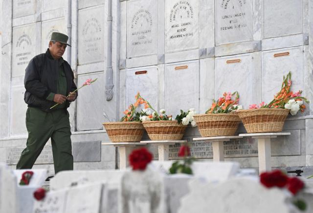 A Cuban soldier places flowers on the graves of some of the 32 Cuban soldiers killed during the US incursion in Venezuela during their funeral at Colon cemetery in Havana on January 16, 2026. The capture by US forces of Venezuelan leader Nicolas Maduro on January 3, 2026, and the killing in the operation of 32 Cubans assigned to protect him represent a major blow for the island's revered intelligence services, experts say. (Photo by Yamil LAGE / AFP)