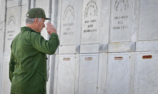Cuba's President Miguel Díaz-Canel salutes the graves of some of the 32 Cuban soldiers killed during the US incursion in Venezuela during their funeral at Colon cemetery in Havana on January 16, 2026. The capture by US forces of Venezuelan leader Nicolas Maduro on January 3, 2026, and the killing in the operation of 32 Cubans assigned to protect him represent a major blow for the island's revered intelligence services, experts say. (Photo by ADALBERTO ROQUE / AFP)