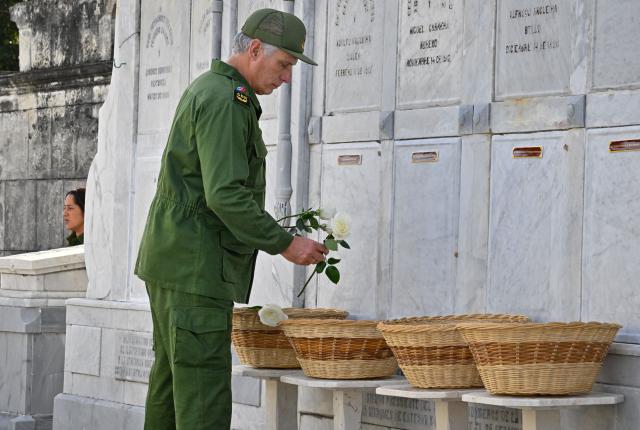 Cuba's President Miguel Díaz-Canel places flowers on the graves of some of the 32 Cuban soldiers killed during the US incursion in Venezuela during their funeral at Colon cemetery in Havana on January 16, 2026. The capture by US forces of Venezuelan leader Nicolas Maduro on January 3, 2026, and the killing in the operation of 32 Cubans assigned to protect him represent a major blow for the island's revered intelligence services, experts say. (Photo by ADALBERTO ROQUE / AFP)
