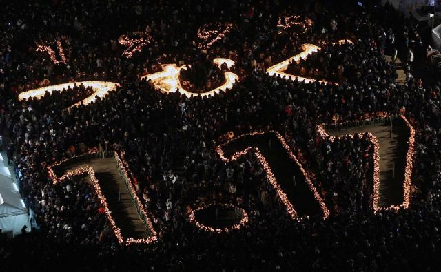 This overhead view shows people taking part in memorial services to mark the 31st anniversary of the "Great Hanshin Earthquake" which devastated the city of Kobe, at Higashi Yuenchi Park in Kobe, Hyogo prefecture on January 17, 2026. The port city of Kobe was hit by a 7.2 magnitude quake on January 17, 1995, killing 6,434 people and levelling much of the city. (Photo by JIJI PRESS / AFP) / Japan OUT