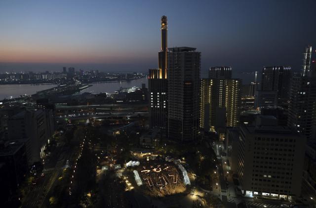 This overhead view shows people taking part in memorial services to mark the 31st anniversary of the "Great Hanshin Earthquake" which devastated the city of Kobe, at Higashi Yuenchi Park in Kobe, Hyogo prefecture on January 17, 2026. The port city of Kobe was hit by a 7.2 magnitude quake on January 17, 1995, killing 6,434 people and levelling much of the city. (Photo by JIJI PRESS / AFP) / Japan OUT