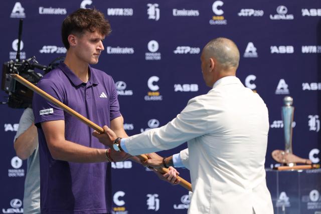 Czech Republic's Jakub Mensik is presented a traditional Maori spear in a ceremony after his victory against Argentina's Sebastian Baez in their men's singles final match at the ATP Auckland Classic tennis tournament in Auckland on January 17, 2026. (Photo by Michael Bradley / AFP)