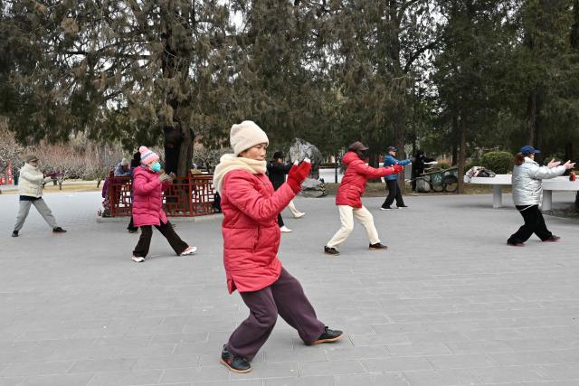 Taichi practitioners move during a session at a park in Beijing on January 17, 2026. (Photo by ADEK BERRY / AFP)