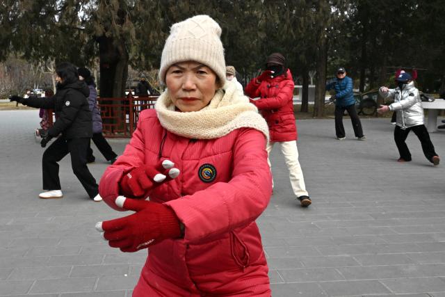 Taichi practitioners move during a session at a park in Beijing on January 17, 2026. (Photo by ADEK BERRY / AFP)